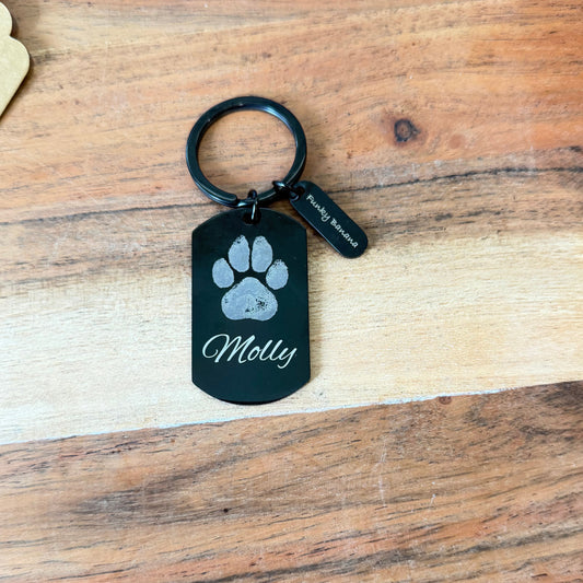 Black keychain with paw print design on a wooden surface